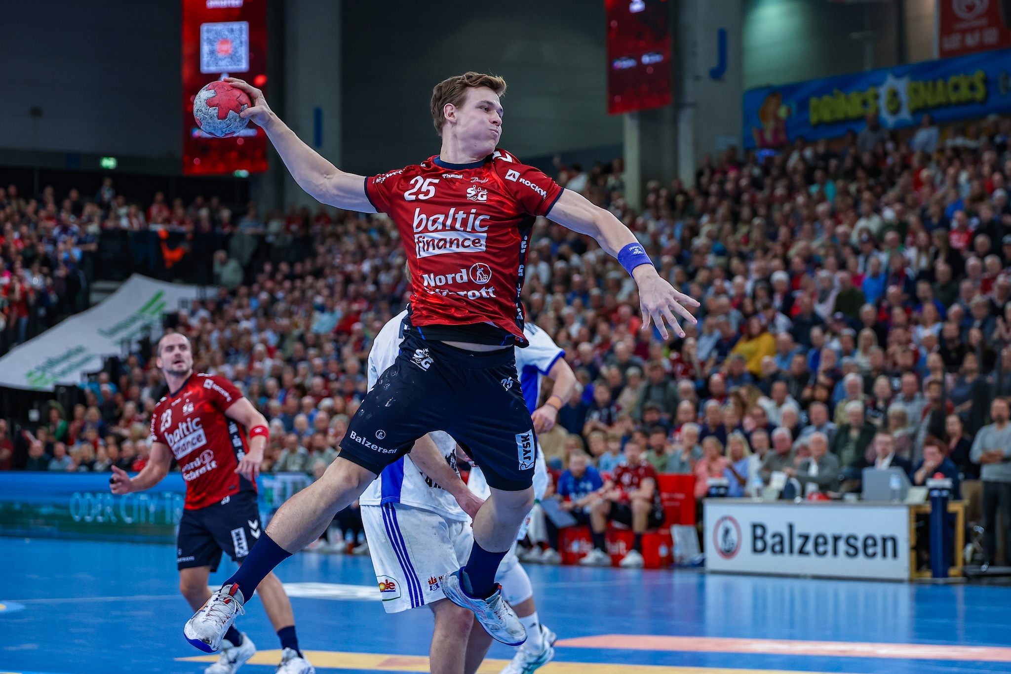 Spieler der SG Flensburg-Handewitt beim Sprungwurf im roten Baltic-Finance-Trikot